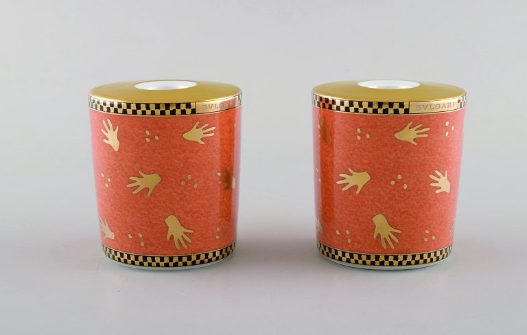 Bvlgari / Bulgari for Rosenthal. Two "Mano al vento" candle holders in porcelain. Orange glaze and gold decoration. Late 20th century.