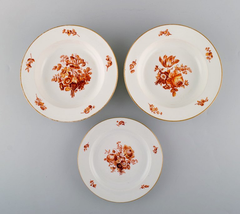 Tre antikke Meissen tallerkener i porcelæn med orange håndmalede blomster. To dybe tallerkener samt frokosttallerken. 1800-tallet.