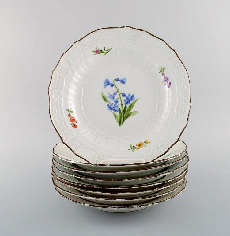 Otte antikke Meissen tallerkener i håndmalet porcelæn med blomstermotiver og guldkant. 1800-tallet.