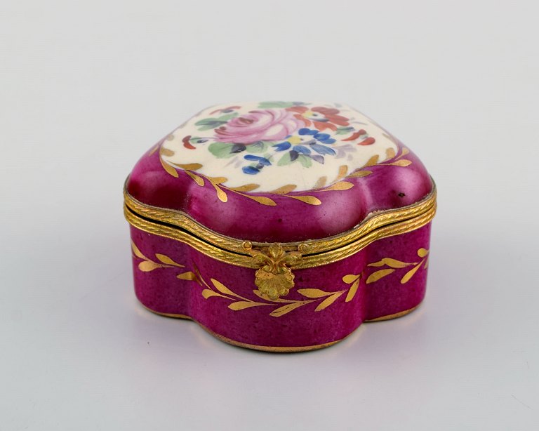 Antique lidded box in hand-painted porcelain with flowers and gold decoration on a purple background. Sevres style, early 20th century.
