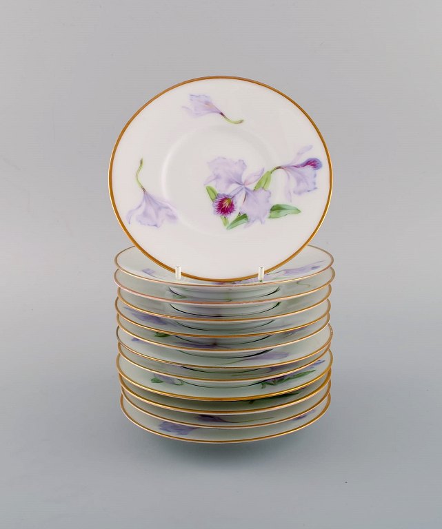 Tolv antikke unika Royal Copenhagen tallerkener i porcelæn med håndmalede lilla lotusblomster. Modelnummer 72/10522. Ca. 1910.