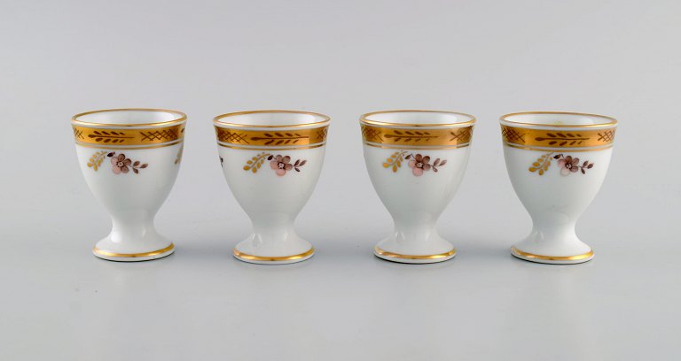 Four Royal Copenhagen Golden Basket egg cups in porcelain with flowers and gold decoration. Model number 595/9110. Early 20th century.