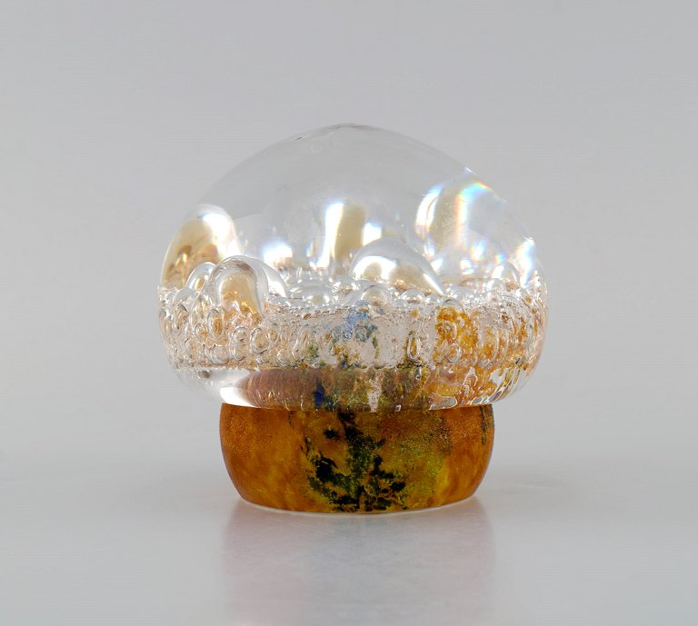 Göran Wärff for Kosta Boda. Paper weight shaped as a mushroom in amber colored and clear mouth-blown art glass with inlaid bubbles. Swedish design, 1970s.