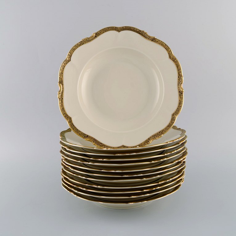 KPM, Berlin. Twelve Royal Ivory deep plates in cream-colored porcelain with gold decoration. 1920s.