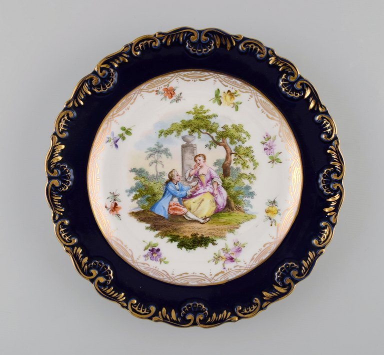 Antik Meissen tallerken i håndmalet porcelæn. Romantisk scene, blå kant med gulddekoration. Sent 1800-tallet.