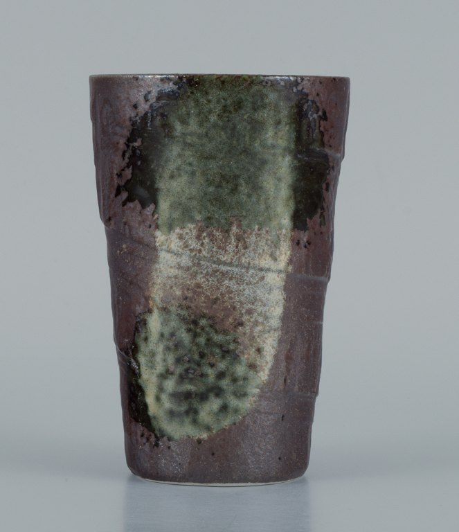 European studio ceramicist. Unique vase in green and white glaze on a brown background.