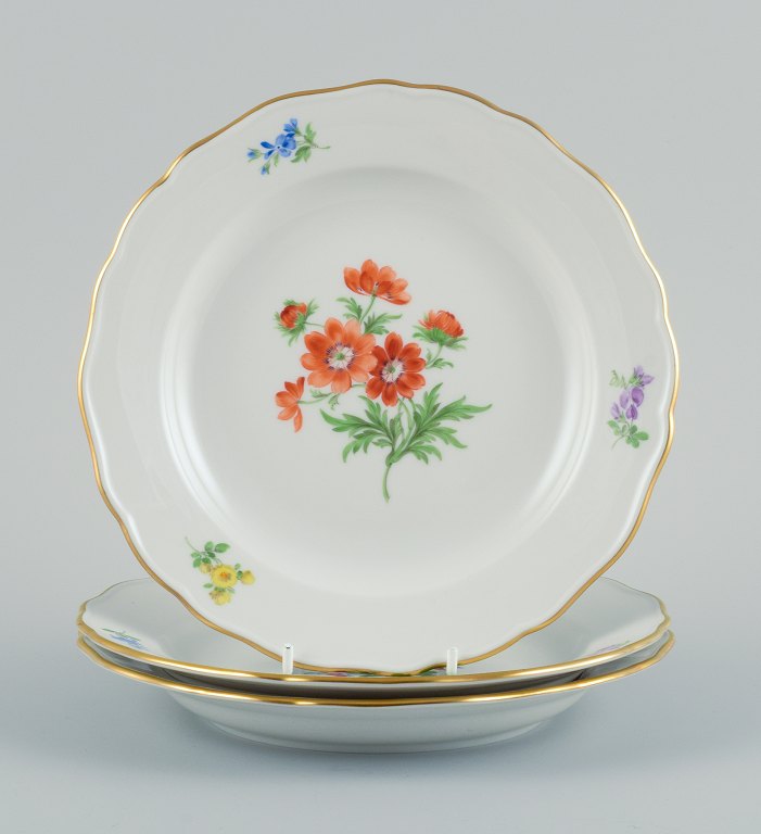 Meissen, Tyskland. Tre porcelænstallerkner håndmalet med forskellige blomstermotiver og guldkant.