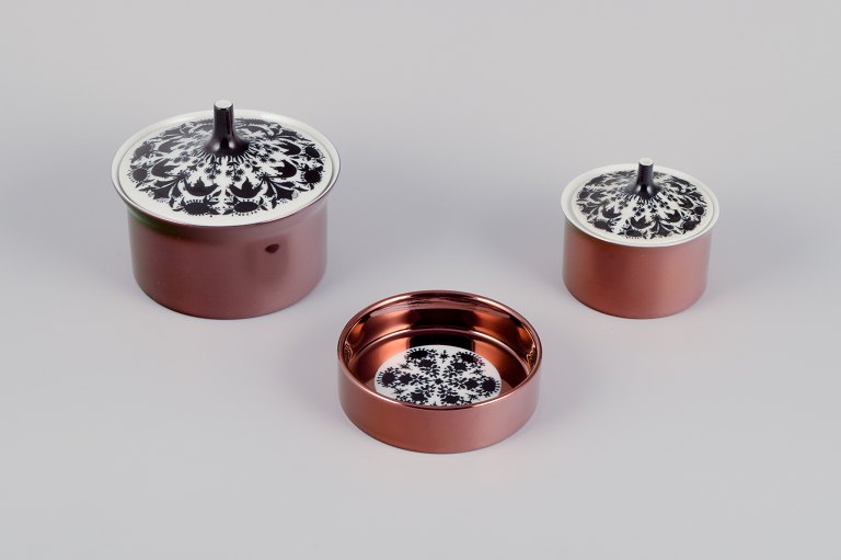 Bjørn Wiinblad for Rosenthal, Tyskland. ”Berlin Hilton”. To lågkrukker og en flaskebakke i porcelæn. Glansfuld kobberfarvet