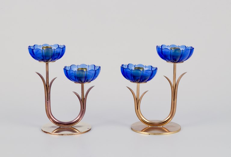 Gunnar Ander for Ystad Metall, Sweden.A pair of two-armed candle holders in brass and blue art glass shaped like flowers.
