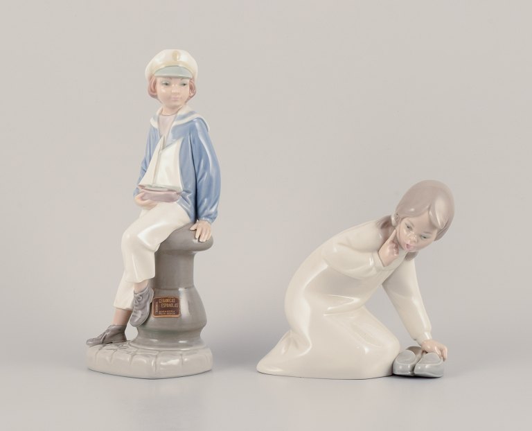 Lladro, Spain. Two porcelain figurines. Boy in sailor outfit with a model ship in hand and a girl figurine.