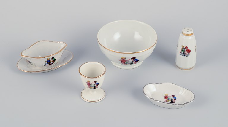 Frankrig børneservice i porcelæn bestående af: Skål, æggebæger, peberbøsse, miniature sauceskål og en lille oval skål. Motiver af børn i leg.