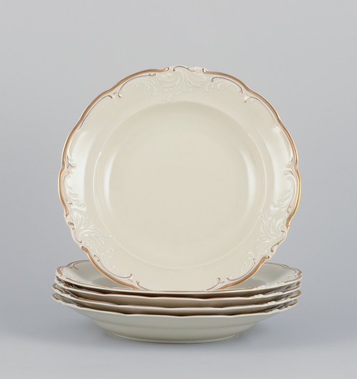 KPM, Poland. A set of five large deep porcelain plates in cream color.Gold-rim decoration.
