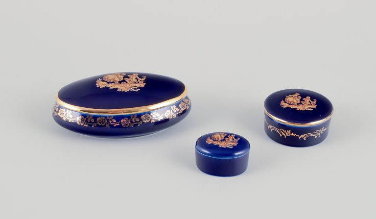 Limoges, France. Three miniature lidded jars in porcelain, decorated with 22-karat gold leaf and a beautiful royal blue glaze. Scène galante.