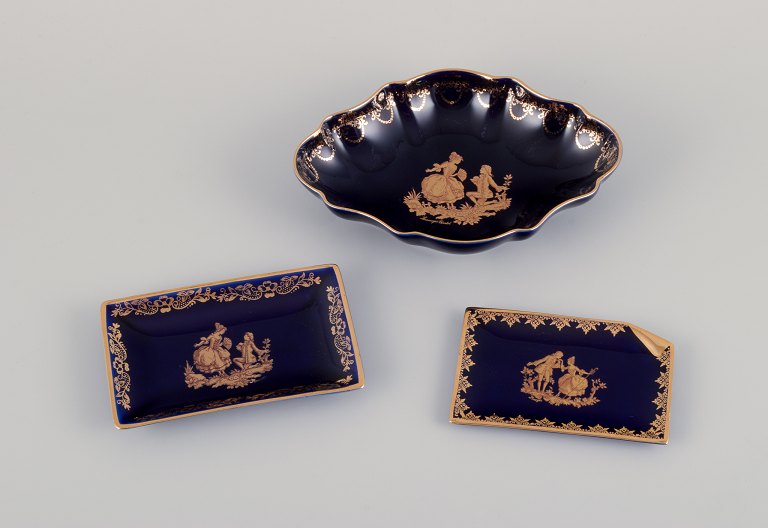 Limoges, France. Bowl and two small trays in porcelain. Decorated with 22-karat gold leaf and beautiful royal blue glaze. Scène galante.