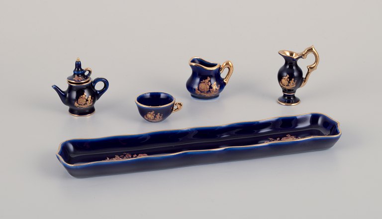 Limoges, France. Miniature porcelain set consisting of a cup, teapot, two pitchers, and a tray. Decorated with 22-karat gold leaf and beautiful royal blue glaze.
