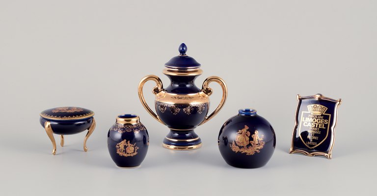 Limoges, France. Five pieces of porcelain consisting of a lidded jar, two vases, a lidded three-footed jar, and a dealer advertising sign. Decorated with 22-karat gold leaf. Beautiful royal blue glaze.
