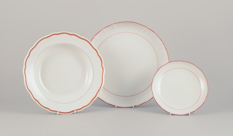 Meissen, Germany. Three-piece porcelain set consisting of a large bowl, a deep plate, and a plate. Decorated with coral red and gold-colored trim. Art Deco.