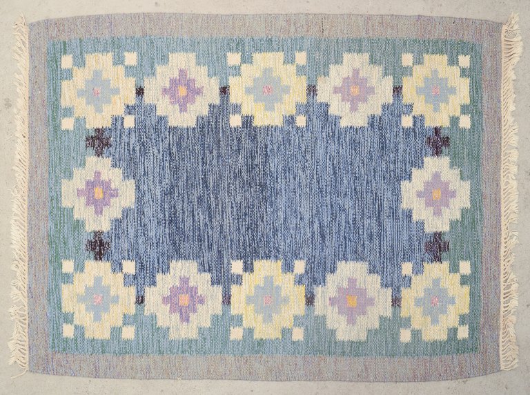 Svensk tekstildesigner.
Håndvævet tæppe af uld. Rölakan teknik. 
Vævet med geometriske felter.